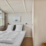 Schlafzimmer mit Bett, Fenster und Holzwand. Wandbild und Schrank sind sichtbar.