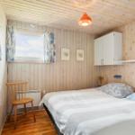 Ein Schlafzimmer mit Holzwänden, einem Bett, einem Stuhl und einem Fenster.