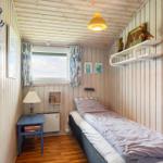 Schlafzimmer mit Bett, Nachttisch und Fenster mit Vorhängen.