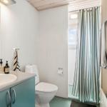 Badezimmer mit Waschbecken, Toilette und Dusche mit Streifenvorhang.