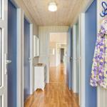 Flur mit Holzboden, blauen Türen und einem weißen Schrank. Eine Jacke hängt an einem Haken.