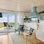 Küche mit Blick auf Terrasse und Strand. Holzdecke, weiße Arbeitsfläche und Sitzgelegenheiten.