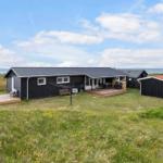 Schwarzes Ferienhaus mit Terrasse und Garten, Blick auf das Meer.