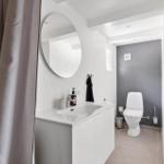 Badezimmer mit Waschbecken, Spiegel und Toilette. Dusche mit Vorhang.