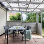 Terrasse mit Tisch, Stühlen und Grill unter Dach