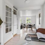 Küche mit Essbereich und Wohnzimmer im Hintergrund. Weiße Wände und Holzböden.