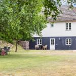 Ein zweistöckiges Haus mit weißem und dunkelblauem Anstrich, umgeben von Gras und Bäumen.