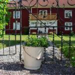 Roter Holzhaus mit Balkon hinter schmiedeeisernem Tor und Pflanzenkasten