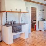 Küche mit altem Ofen, Holzboden und Treppe im Hintergrund.