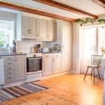 Küche mit Holzboden, weißen Schränken und Holzbalken an der Decke.