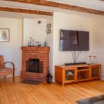 Wohnzimmer mit Kamin, Fernseher und Holzboden. Möbel und Bilder sorgen für gemütliche Atmosphäre.