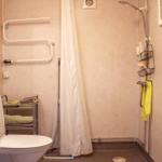 Bad mit Dusche, WC und Waschbecken. Handtuchhalter und Duschbrause sichtbar.