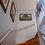 Hausflur mit Treppe, Wandbildern und weißen Geländern.