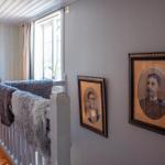 Wohnbereich mit Holzboden, Fenster und zwei gerahmten Porträts an der Wand.