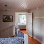 Hausflur mit Treppenhaus, Bildern an der Wand und Blick in Schlafzimmer mit Bett.