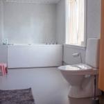 Badezimmer mit Badewanne, Toilette und Waschbecken mit Holzschrank.