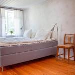 Schlafzimmer mit Bett, Stuhl und Fenster. Holzfußboden und Wand mit Muster.