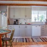 Küche mit Holzboden, hellen Schränken und Essbereich mit Tisch und Stühlen.