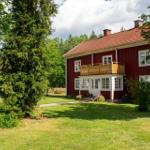 Rotes Holzhaus mit Balkon und grünem Garten. Hinterhof mit Tisch und Stühlen.
