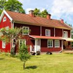 Rotes Holzhaus mit Terrasse und Garten. Mehrere Fenster und Schornsteine sind sichtbar.