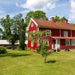 Rotes Holzhaus mit Terrasse und Garten unter blauem Himmel.