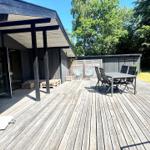 Terrasse mit Tisch, Stühlen und Pavillon. Hinterhof mit Holzhaus und Bäumen.