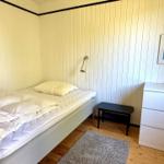 Schlafzimmer mit Bett, Nachttisch und Schrank an Holzwand
