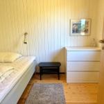 Schlafzimmer mit Bett, Schrank, Nachttisch und Wandbild.