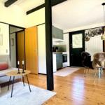 Wohn- und Essbereich mit Küche. Holzboden, Sofa, Tisch und Stühle mit Felldecken.