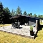 Holzterrasse mit Tisch, Stühlen und Pflanze vor einem Haus mit Schuppen