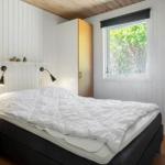 Schlafzimmer mit Bett, Fenster und Holzwandverkleidung.