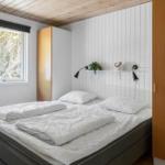 Schlafzimmer mit Bett, Fenster und Schrank. Wand mit Regal und Lampen.