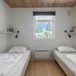 Zwei Einzelbetten mit weißen Laken stehen in einem Raum mit Holzfußboden und weißem Paneelwandverkleidung.