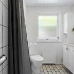 Badezimmer mit Toilette, Waschbecken und Dusche. Fenster mit getöntem Glas.