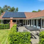 Haus mit Solaranlage, Terrasse und Garten. Holzterrasse mit Liegen und Grill.