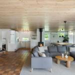 Wohnzimmer mit Kamin, Sofa und Küchenbereich unter Holzdecke.
