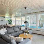 Wohnzimmer mit Sofa, Kamin und Blick auf Pool