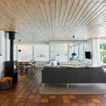 Wohnzimmer mit Sofa, Kamin und Terrassentür. Holzdecke und Fliesenboden.