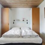 Schlafzimmer mit Doppelbett, Holzdecke und Fenster mit Blick auf Grün.