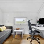 Ein Raum mit Sofa, Schreibtisch und Fenster mit Blick auf Gras.
