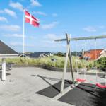 Terrasse mit Schaukel, Tisch und dänischer Flagge. Hintergrund: Gras und Häuser.