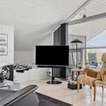 Wohnzimmer mit Sofa, Sessel und TV. Große Glasfront mit Blick auf die Landschaft.