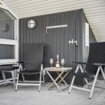 Terrasse mit zwei Stühlen, Tisch und Flasche. Hintergrund: Hauswand und Fenster.