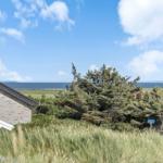 Blick auf das Meer mit Grasland und Bäumen. Haus mit grauer Fassade und Dach.