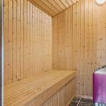 Sauna mit Holzwandverkleidung und Sitzbank. Ecke mit lila Mülltonne.