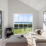 Wohnzimmer mit Sofa, Fernseher und Blick auf den See.
