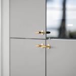 Moderne Schrankfronten mit goldenen Griffen und Glasfront.