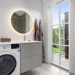 Badezimmer mit Waschmaschine, Spiegelschrank und Glastür zum Garten.