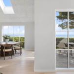 Durchgehendes Wohn- und Esszimmer mit Blick auf den Strand und Garten.