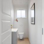Badezimmer mit Toilette, Waschbecken und Fenster. Wandbild und Holzdekoration.